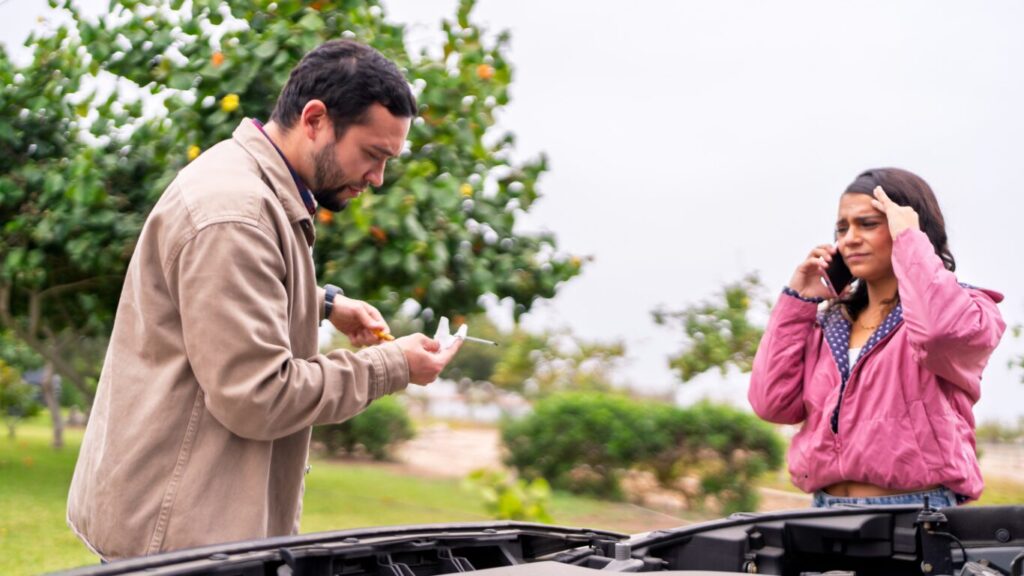 Man controleert oliepeil langs de weg terwijl bestuurder hulp belt bij autopech in regio Zwanenburg.